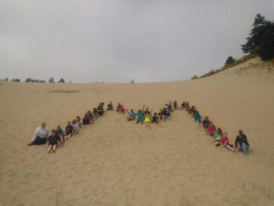 Students forming a letter M on the sand dunes